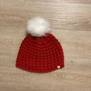 Red beanie with white fuzzy ball on top.